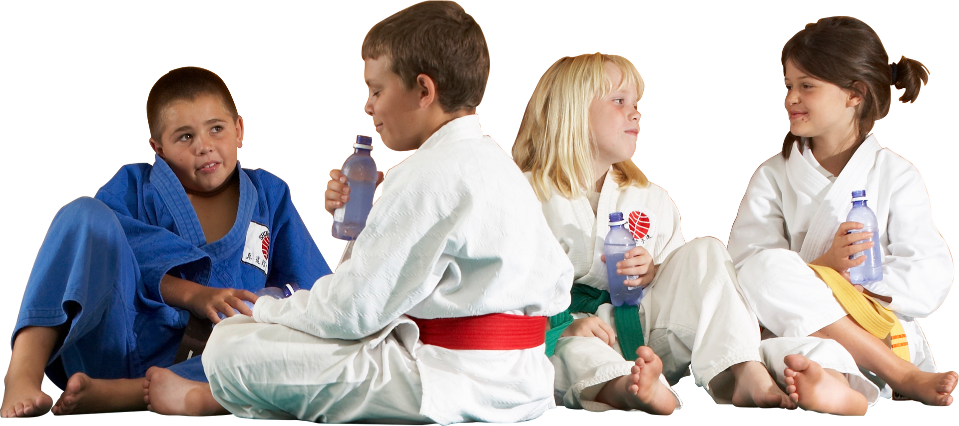 A group of kids in karate uniforms are sitting on the floor drinking water