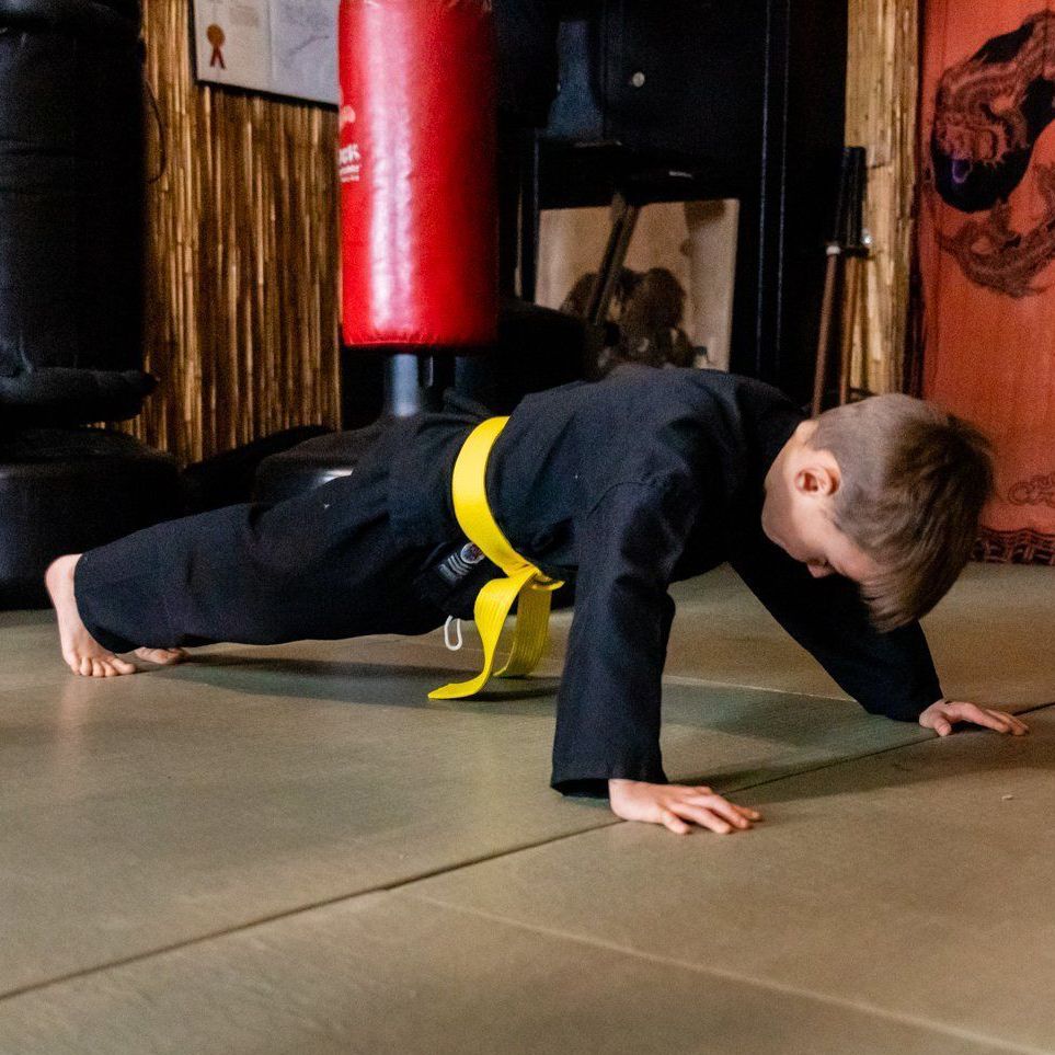 A young boy is doing push ups on the floor