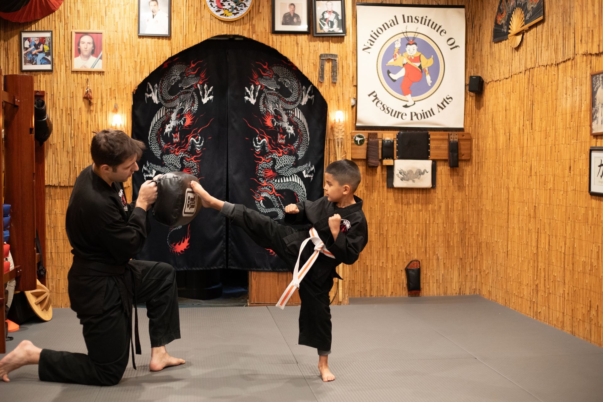 A man and a boy are practicing martial arts in a gym.