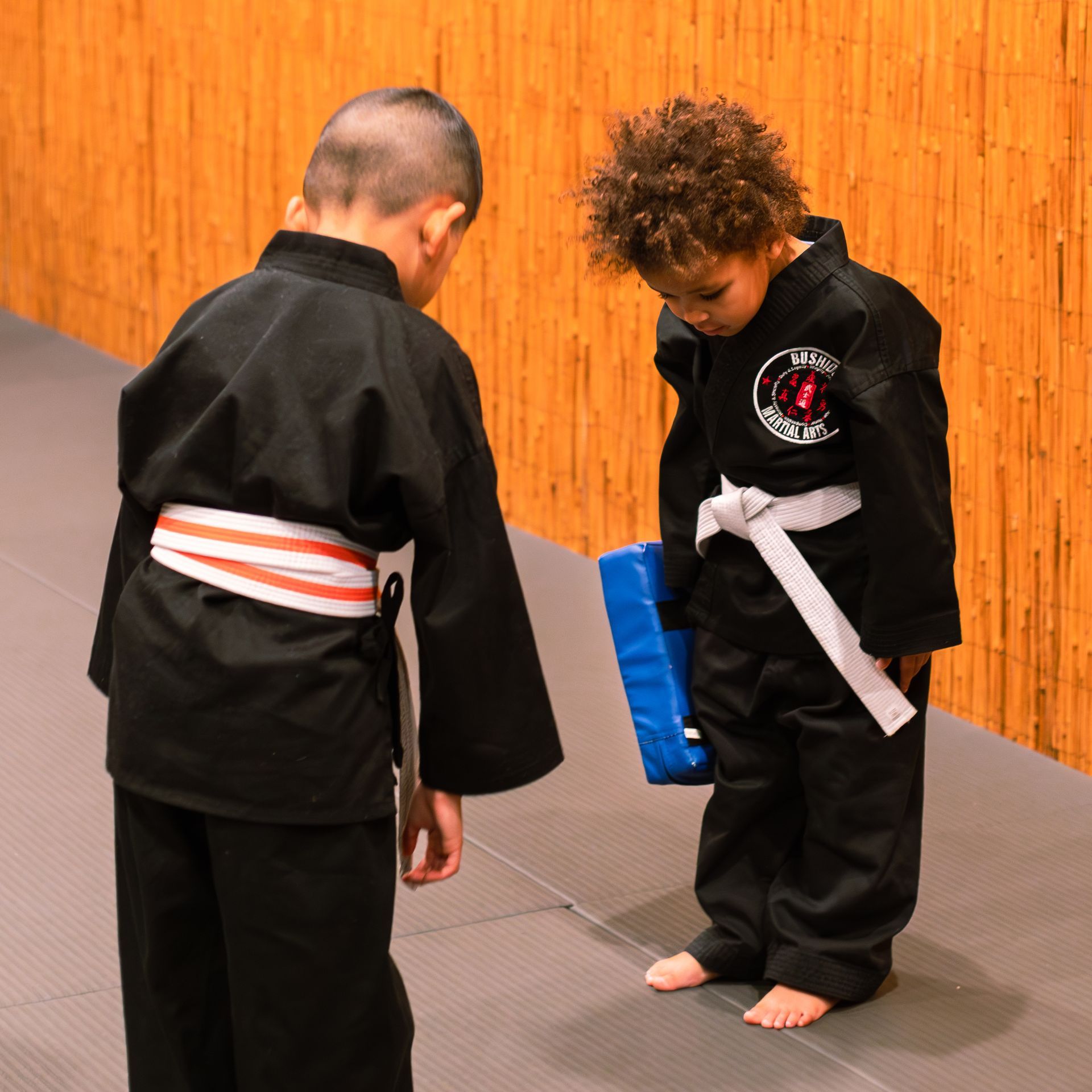 Two young boys in karate uniforms are standing next to each other