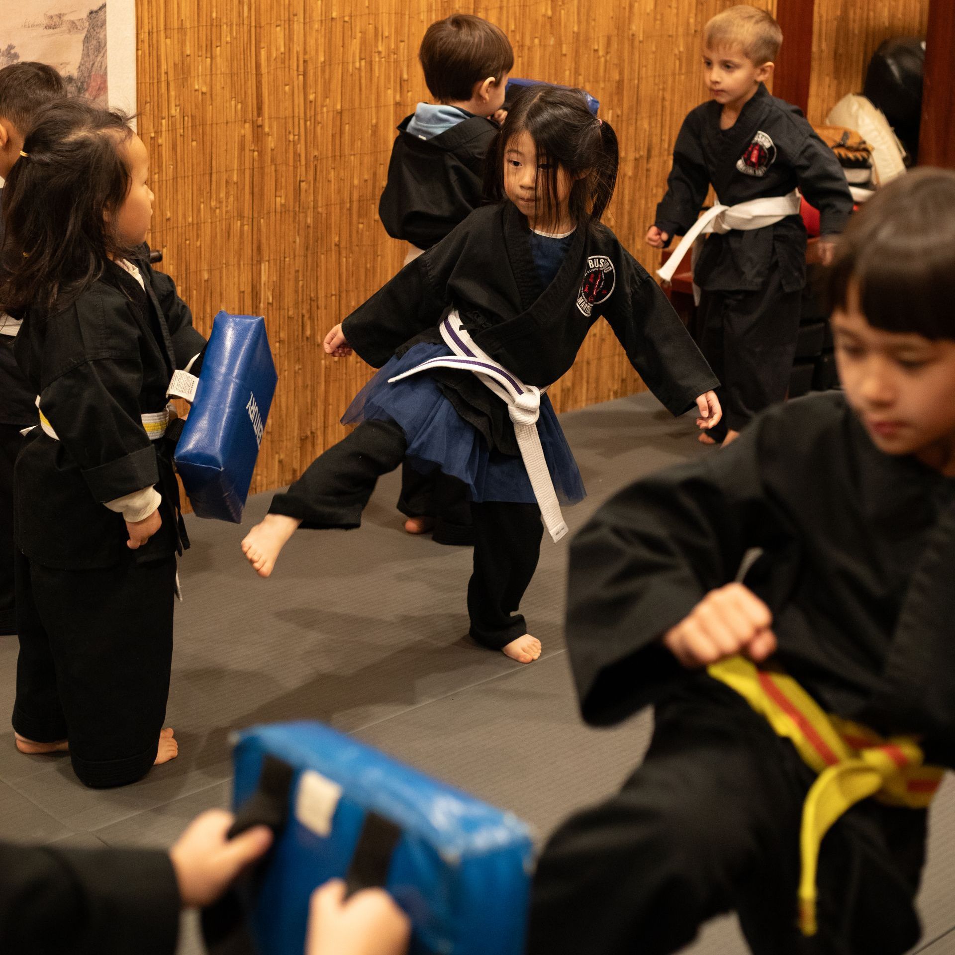 A group of children are practicing martial arts in a gym