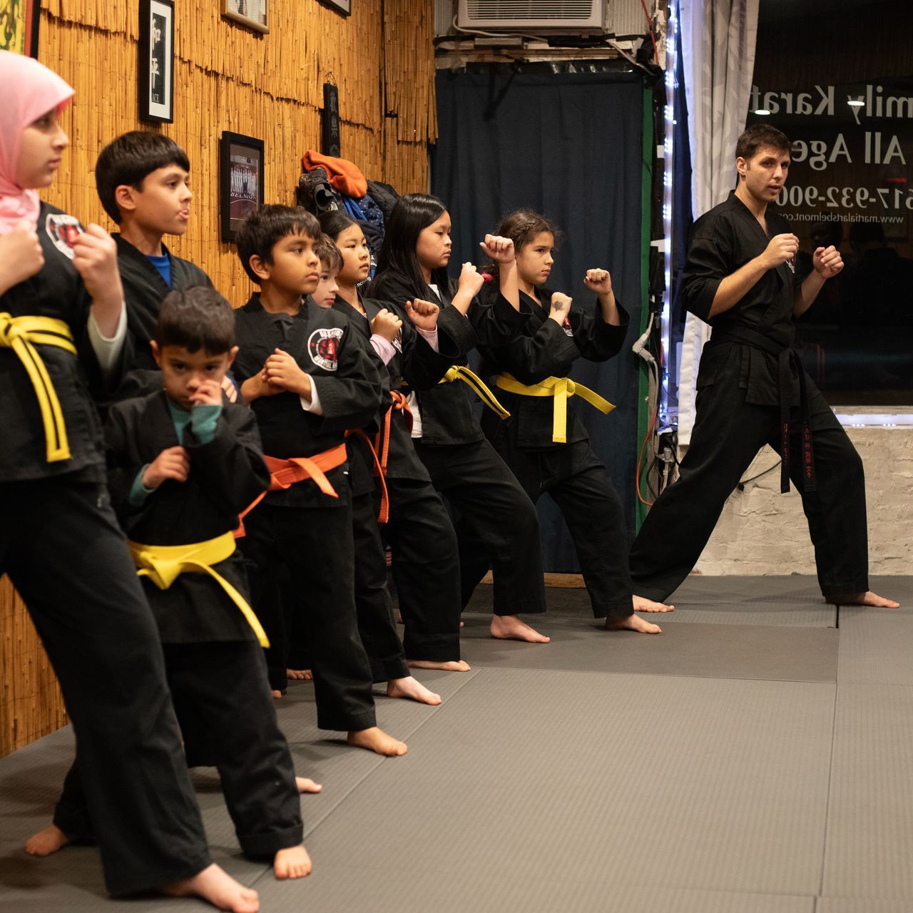 A group of kids are practicing martial arts in a gym