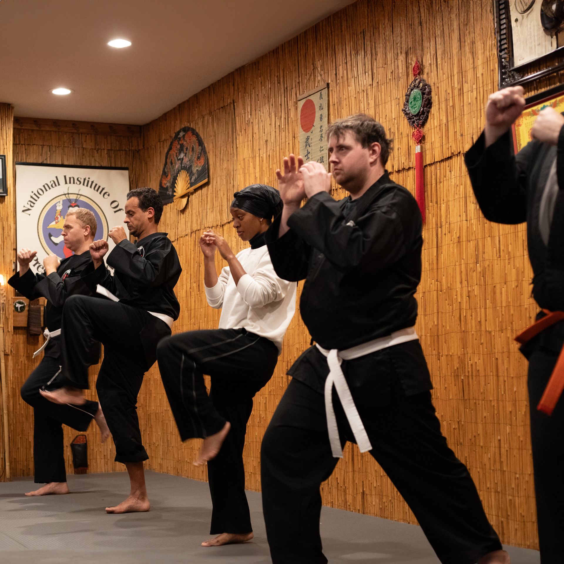 A group of people are practicing martial arts in front of a sign that says national history of martial arts