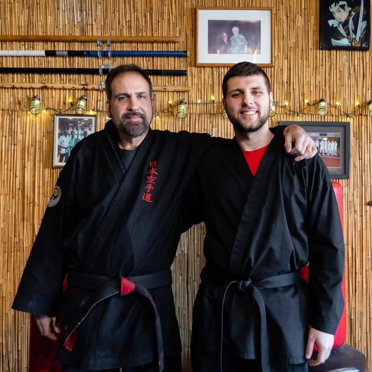 Two men in black karate uniforms pose for a picture
