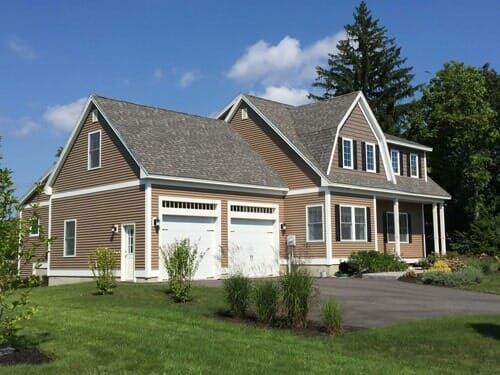 A large brown house with a gray roof and two garages