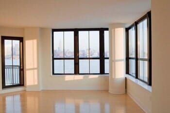 An empty room with a lot of windows and a view of the city.