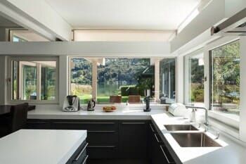 A kitchen with two sinks and a lot of windows.