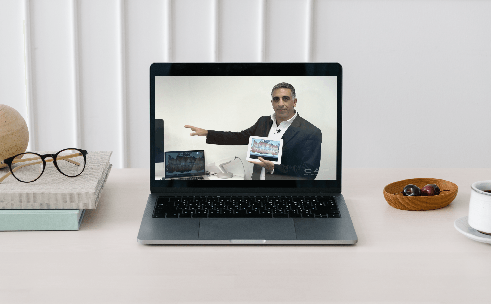 A laptop computer is open to a video of a man holding a book.