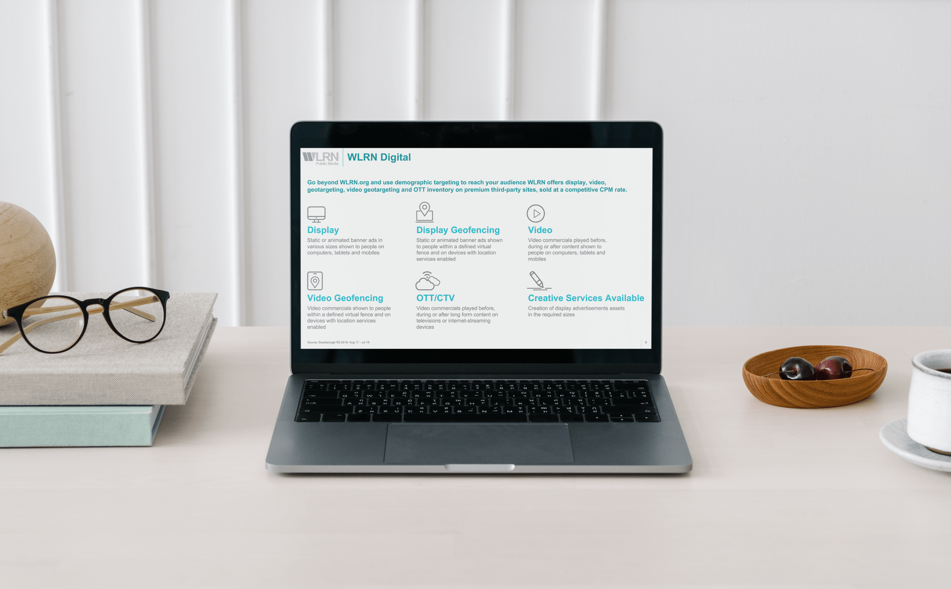 A laptop computer is sitting on a desk next to a cup of coffee and glasses.