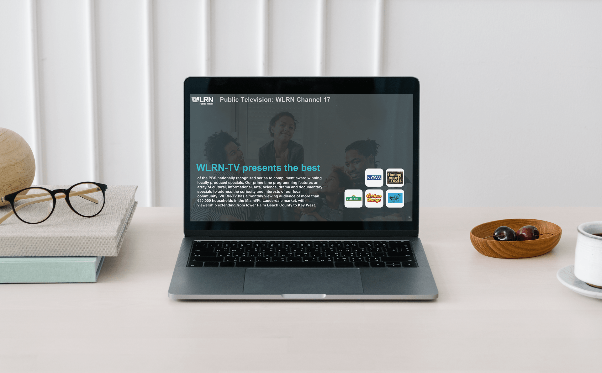 A laptop computer is sitting on a desk next to a stack of books and glasses.