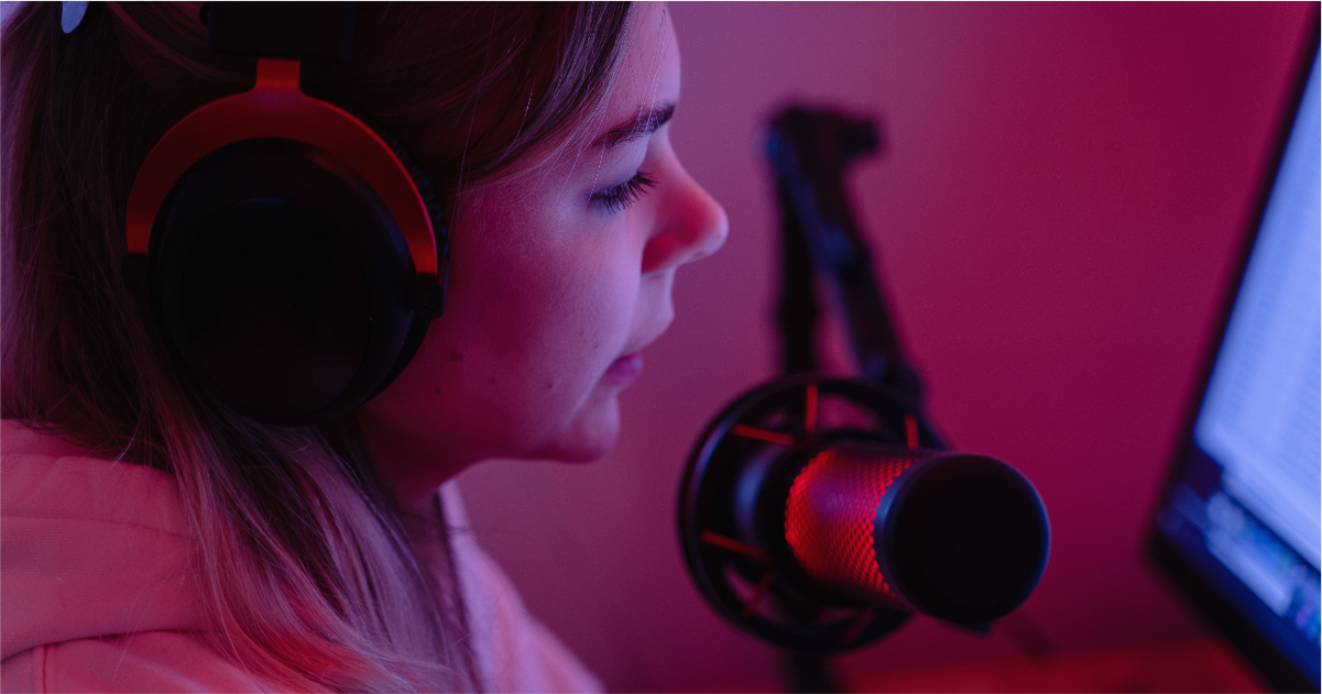 A woman wearing headphones and a microphone is sitting in front of a computer.