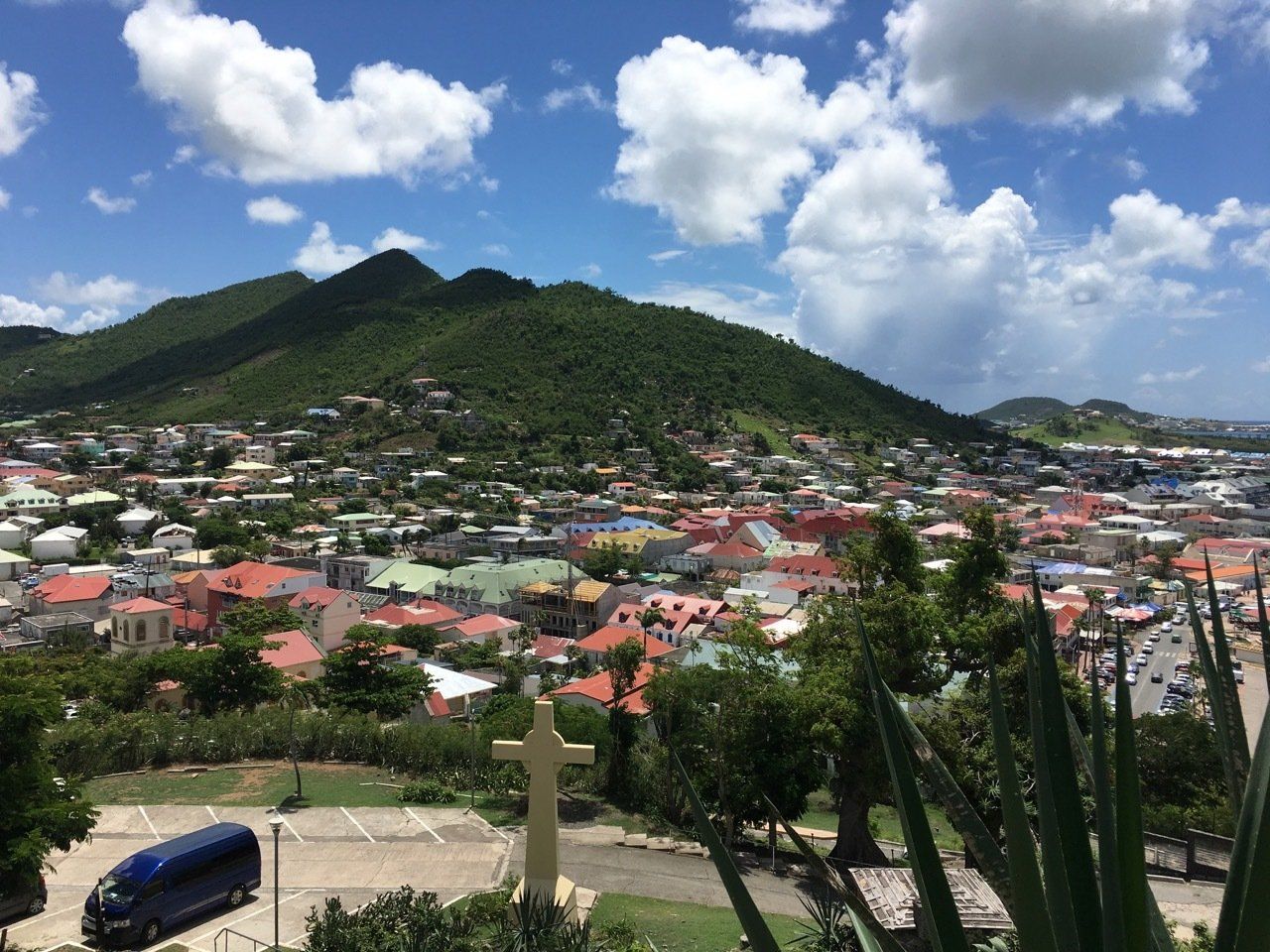 A view of a city from a hill with a cross in the foreground.