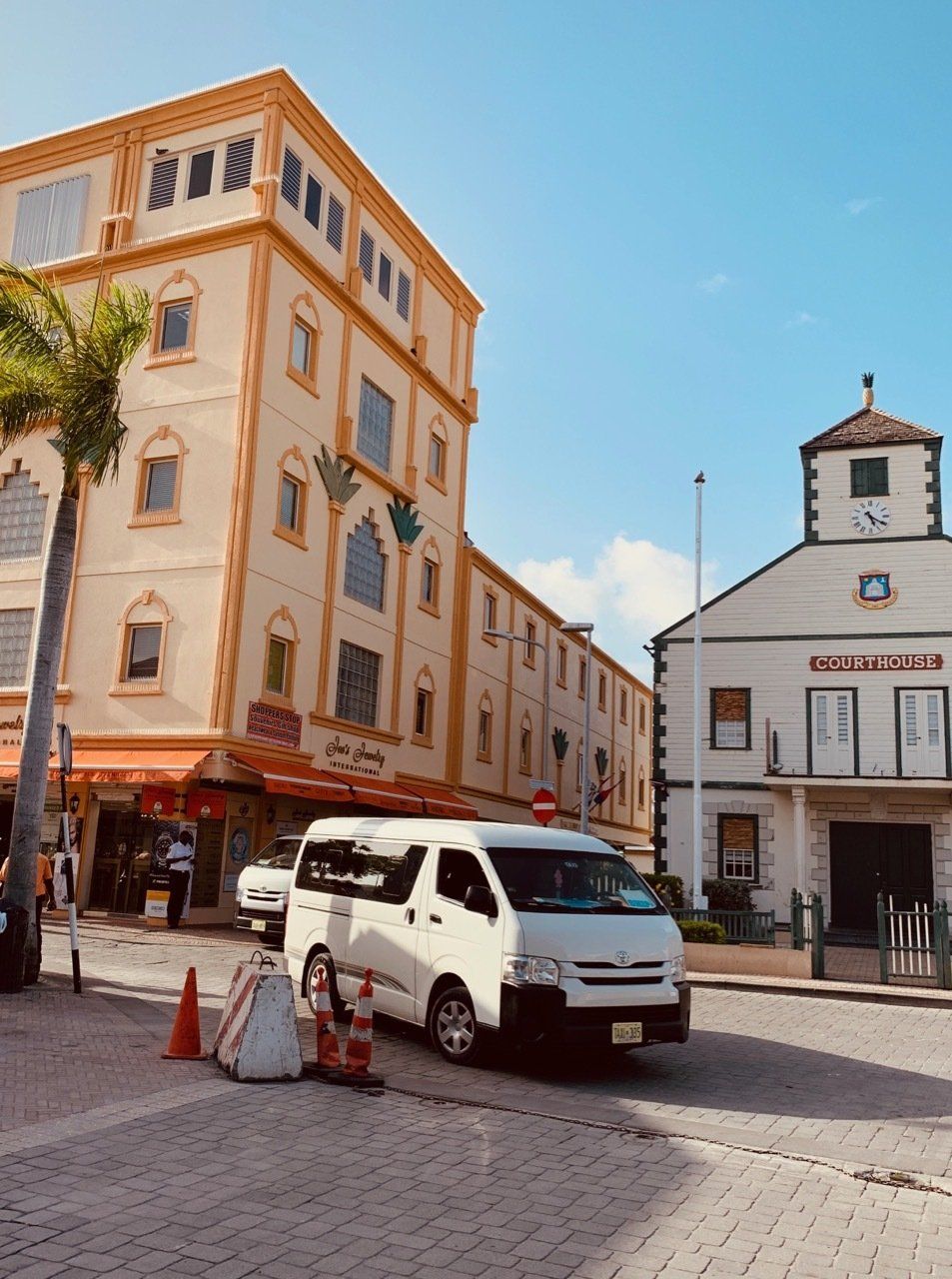 A white van is parked in front of a large building