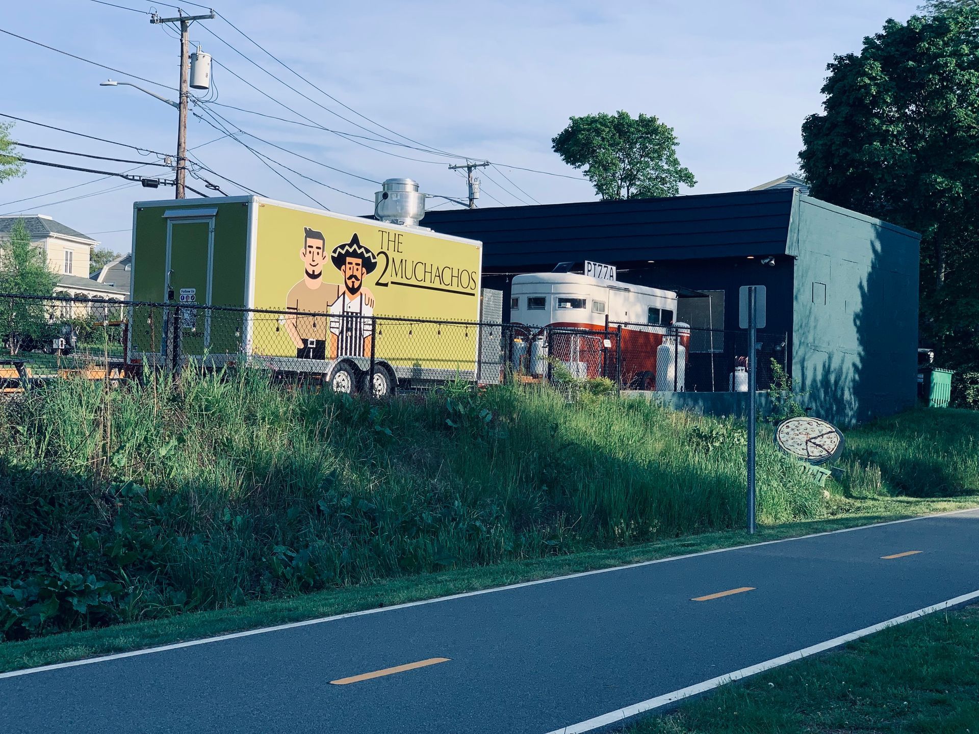 A yellow food truck is parked on the side of the road. Pizza Shop