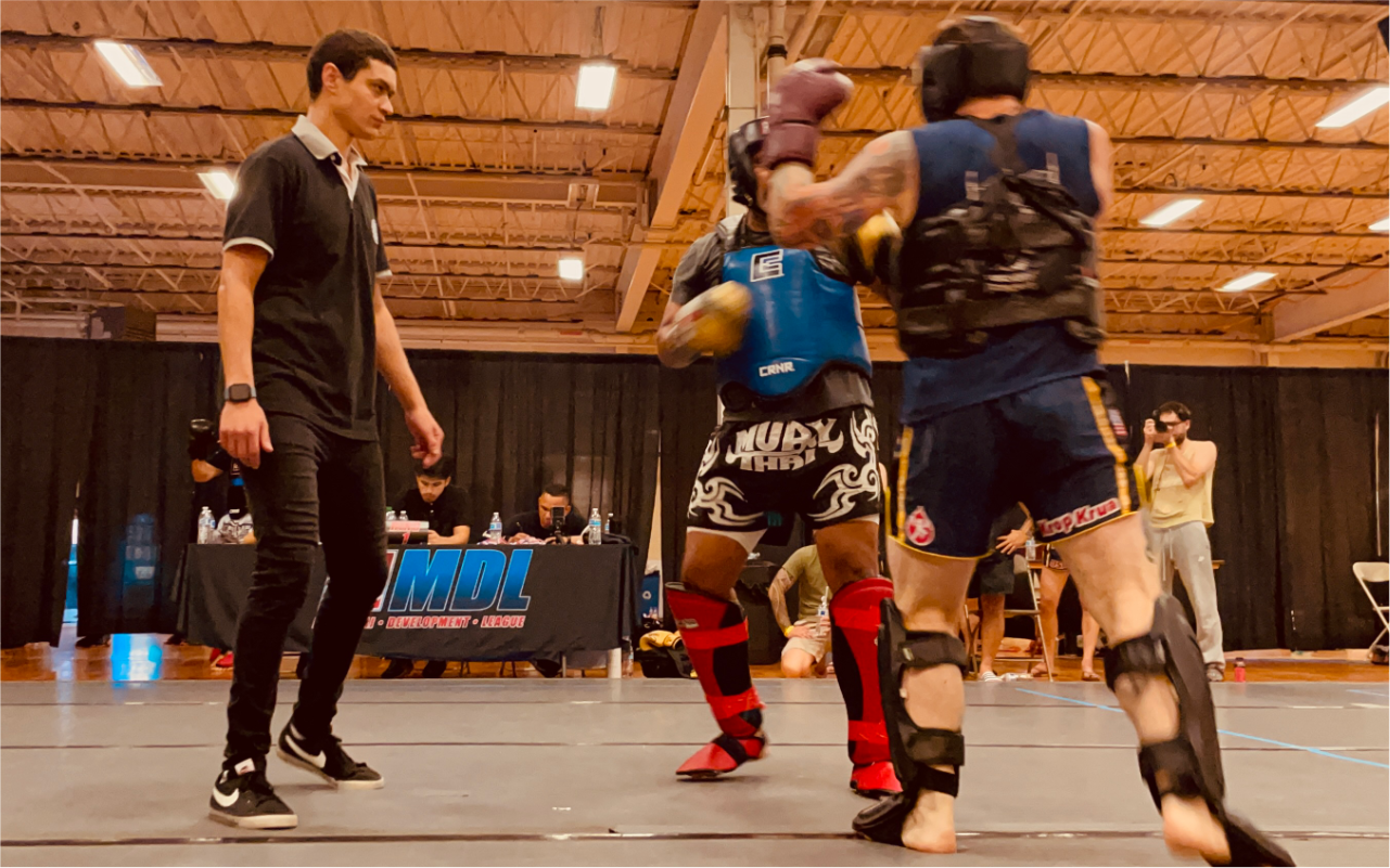 A referee is standing in the middle of a boxing match.