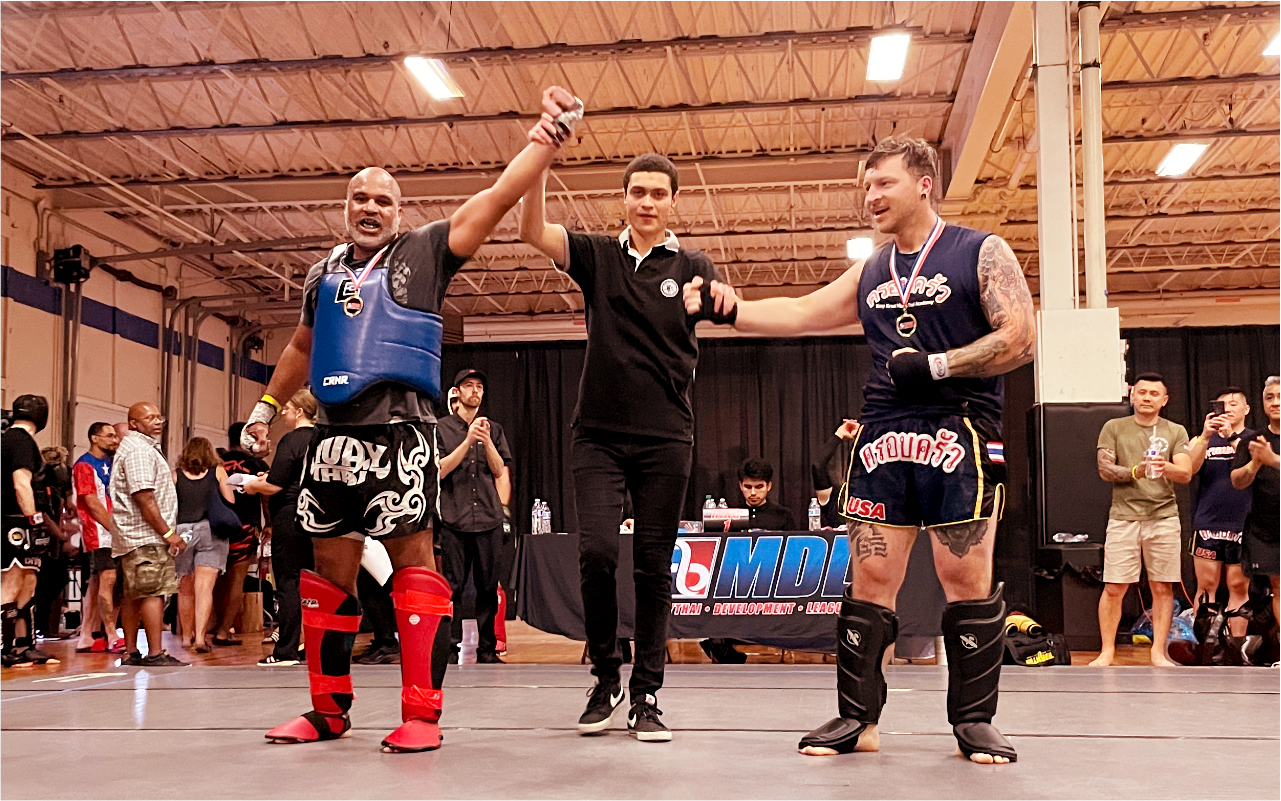 Three men are standing next to each other in a muay thai boxing ring.