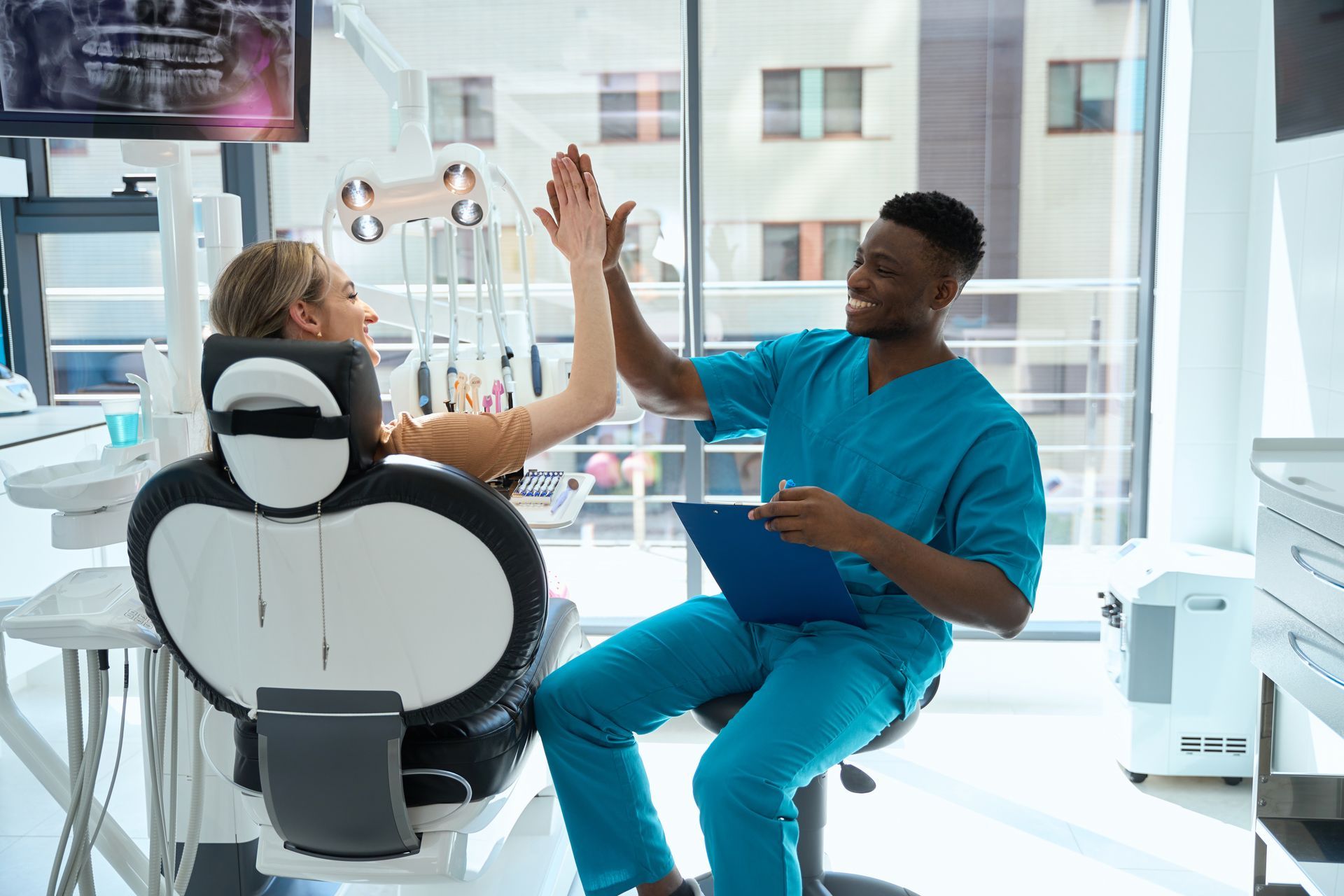 A dentist is giving a patient a high five in a dental office.