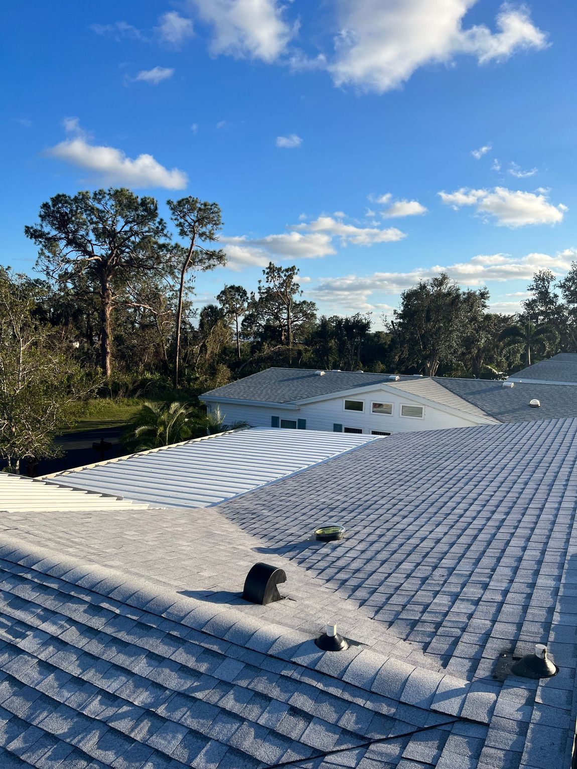 A roof with a blue sky and trees in the background