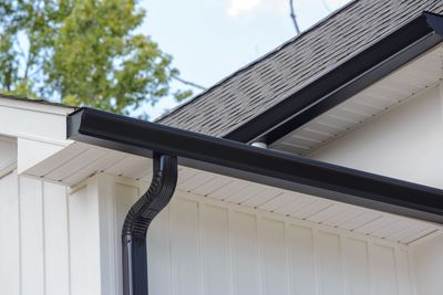 A close up of a black gutter on the side of a house.