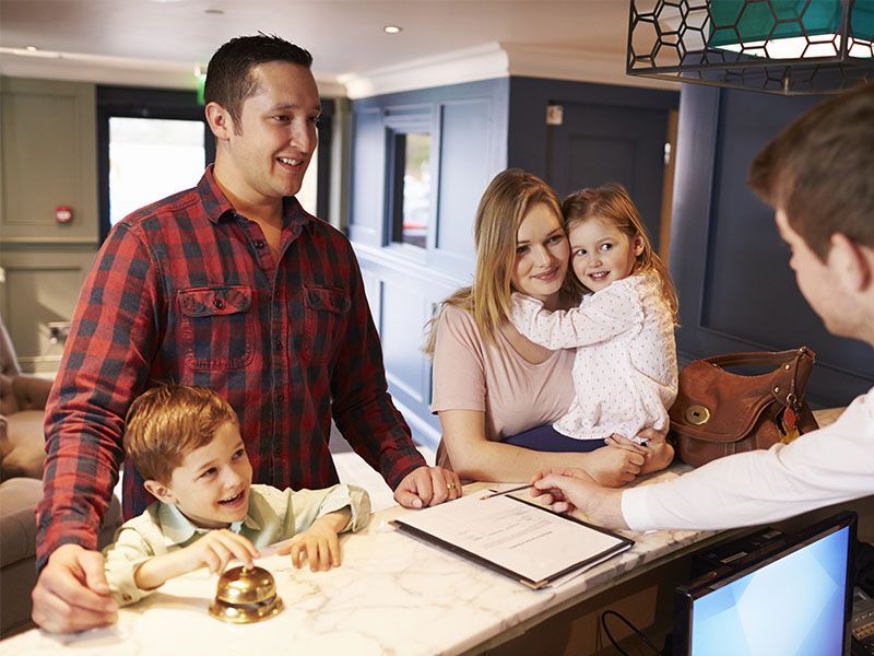 A family is checking in at a hotel reception desk.