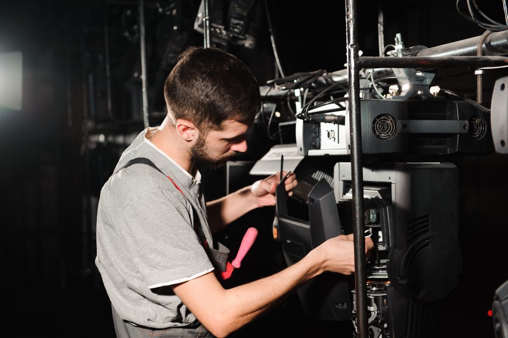A Person In A Gray Shirt, Using A Screwdriver, Works On Stage Lighting — Kennedy Amplifier Hire Service In South Mackay, QLD