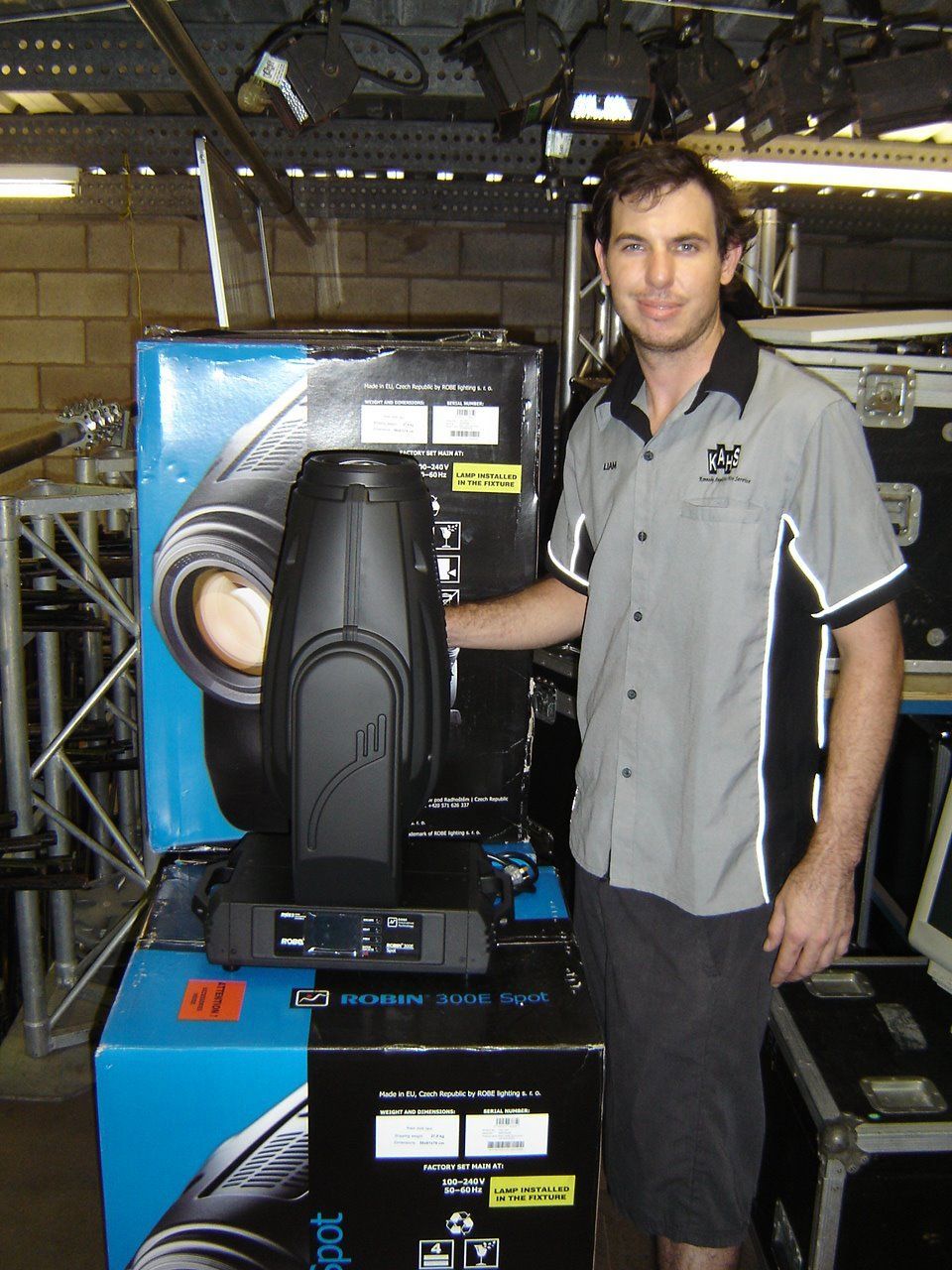 Man Standing Next To A Stage Light And Box — Kennedy Amplifier Hire Service In South Mackay, QLD