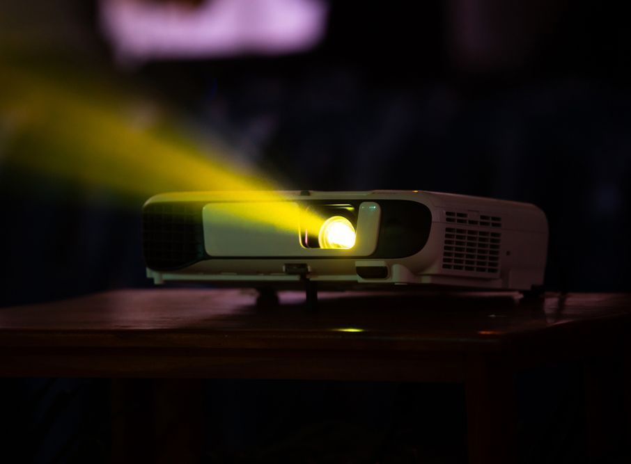 Projector Emitting Bright Yellow Light Onto A Dark Surface — Kennedy Amplifier Hire Service In South Mackay, QLD