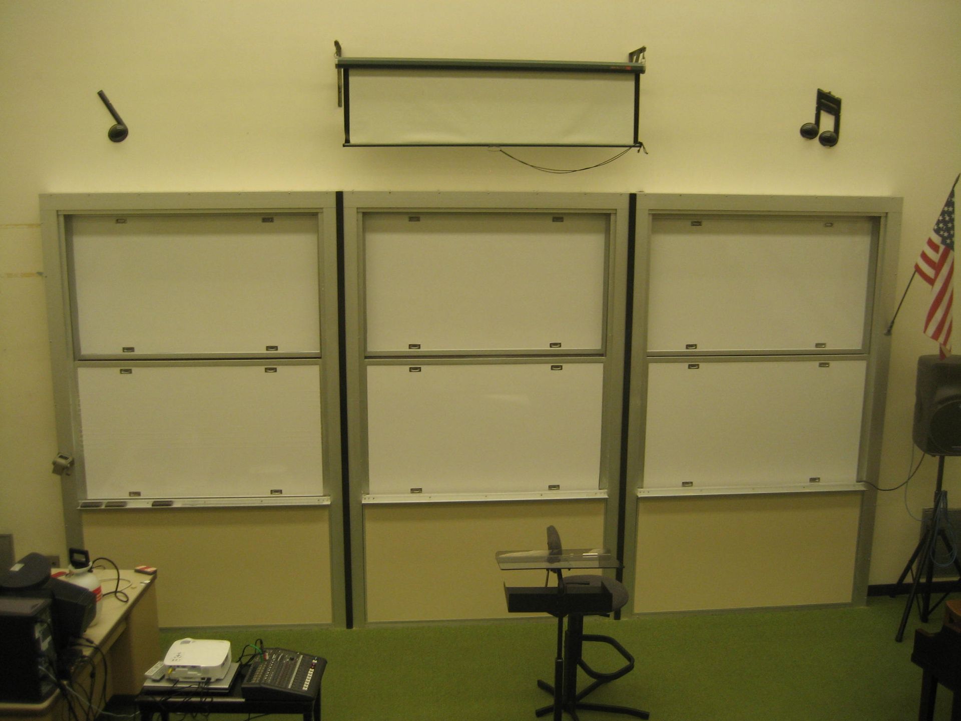 Empty classroom whiteboard wall with three whiteboards, black music note decor, and a microphone stand