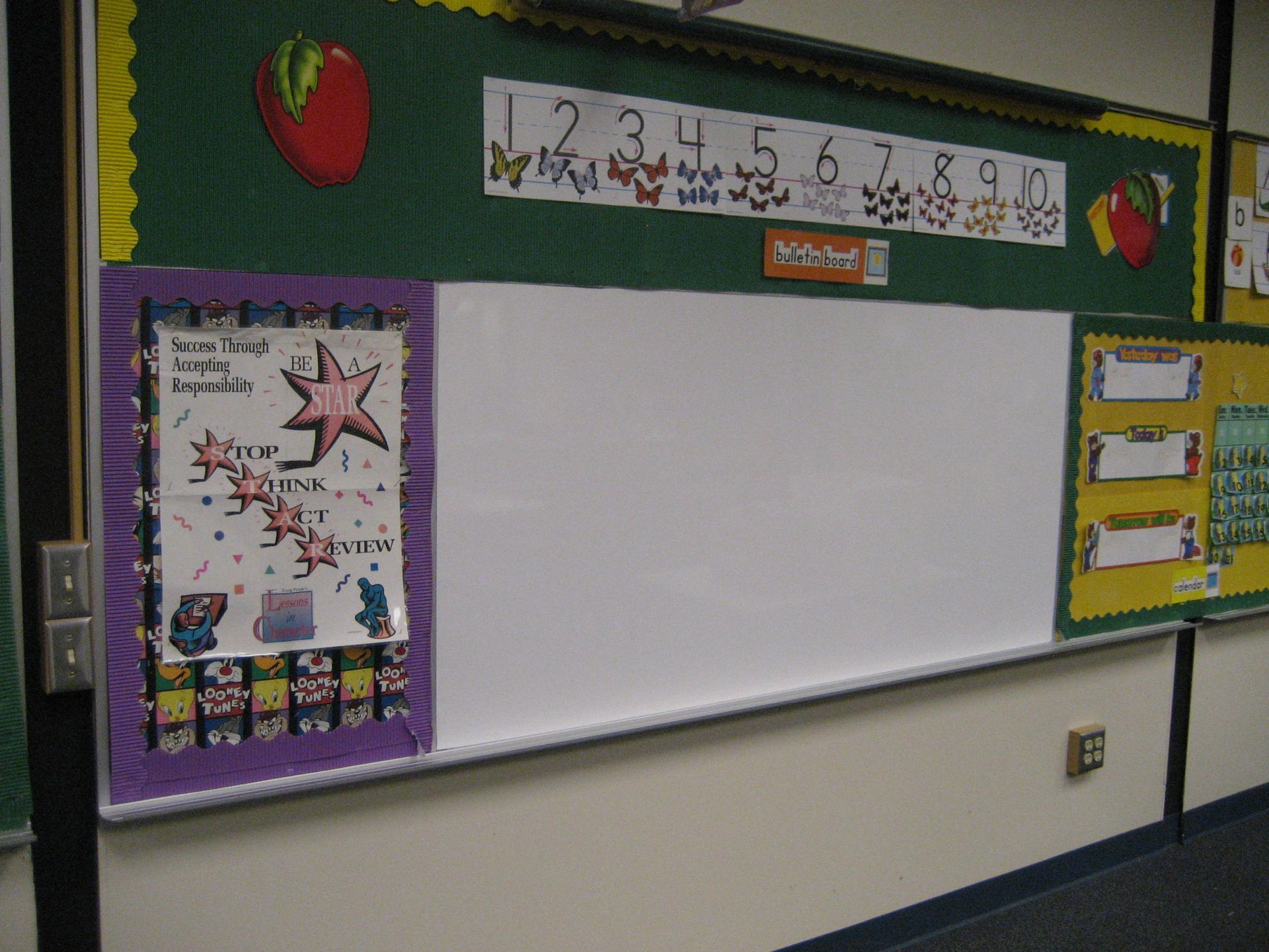 Classroom whiteboard with colorful decorations, number chart, and purple and yellow bulletin boards