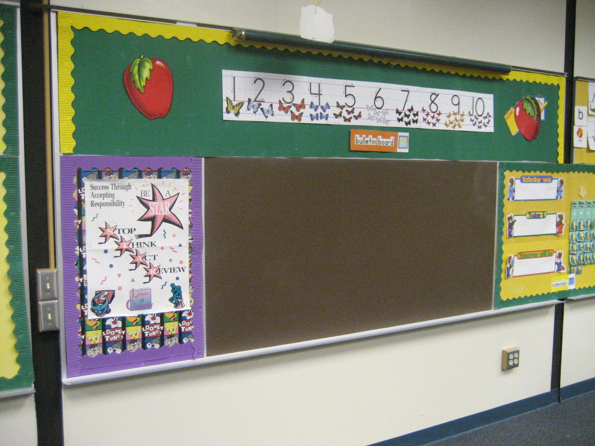 Elementary classroom bulletin board with a blank chalkboard and colorful student work displays