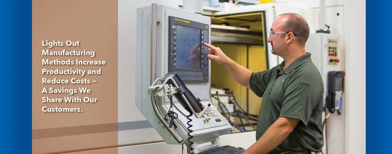 A man is standing in front of a computer in a factory.