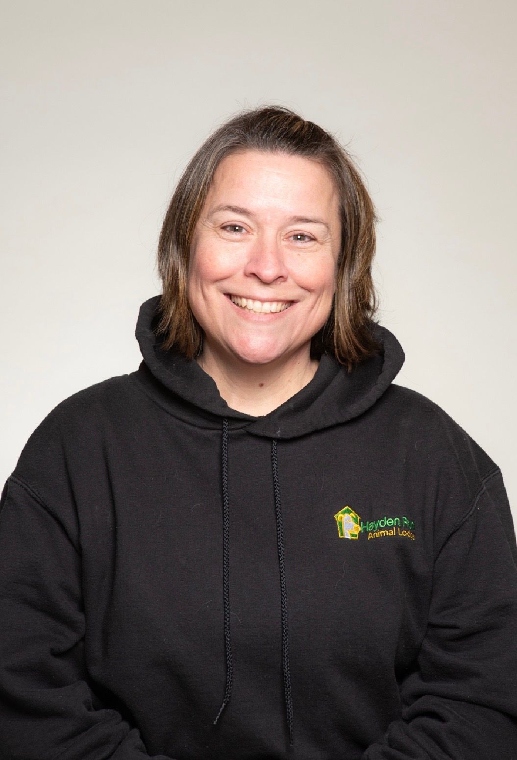 Woman with curly hair smiles broadly, wearing a white tank top.