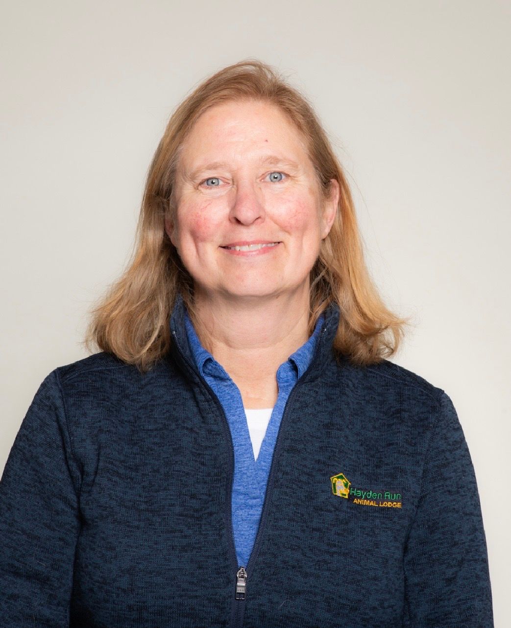 Woman with curly hair smiles broadly, wearing a white tank top.