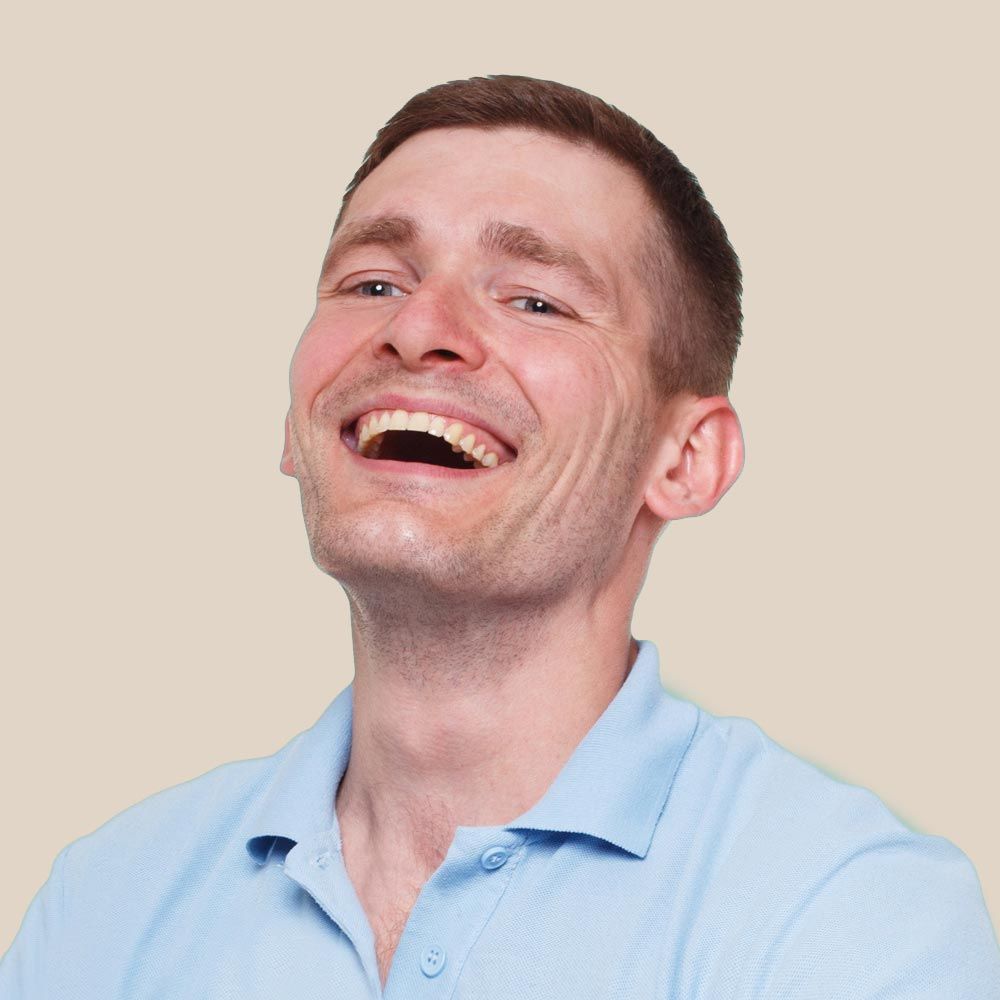 Man with short brown hair wearing a light blue polo shirt, laughing with mouth open.