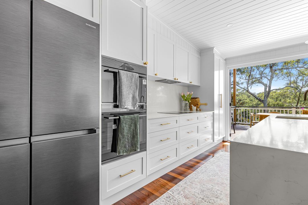 Modern white kitchen with stainless steel appliances, cabinets, and an open view.
