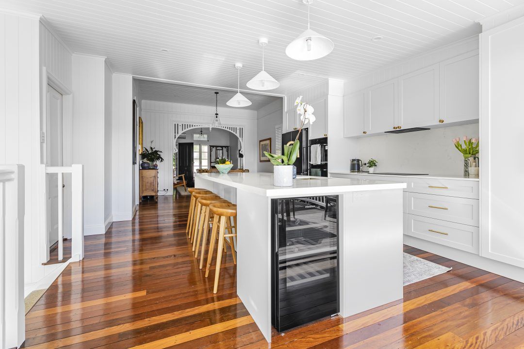 Bright, white kitchen with wood floors, island seating, and cabinets.