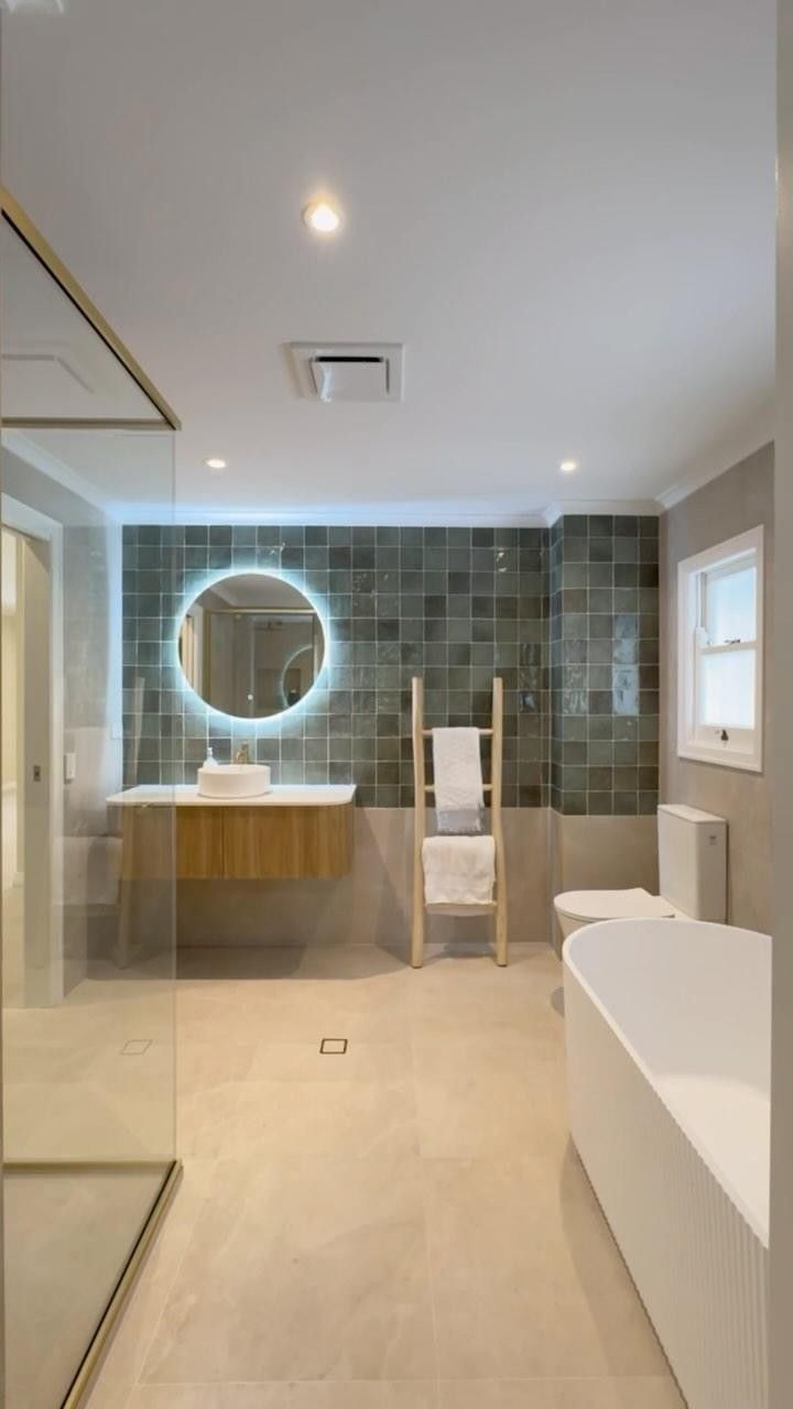 Modern bathroom with a wooden vanity, round mirror, and freestanding bathtub.