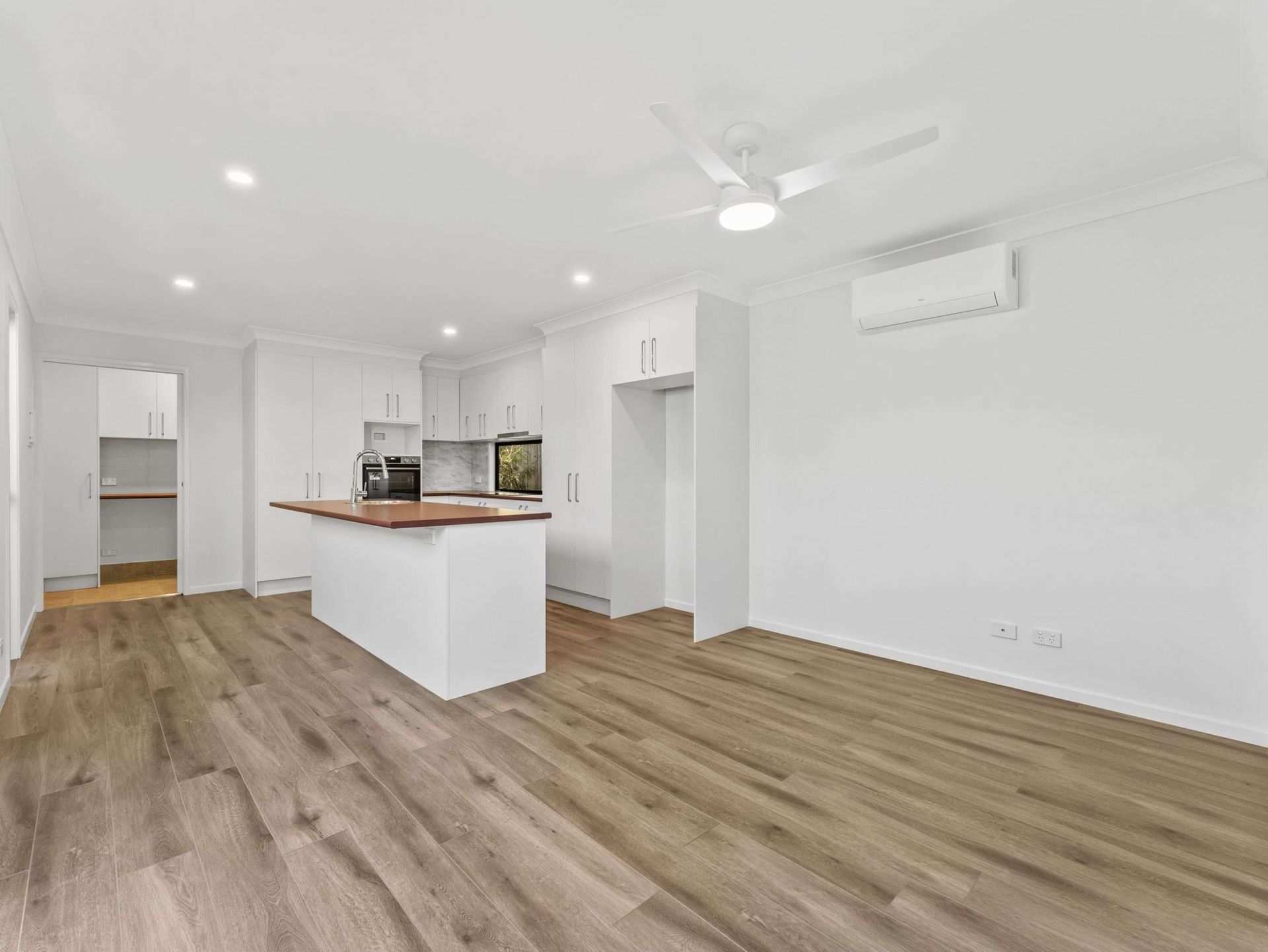 Open-concept kitchen with white cabinetry, a wood-topped island, and wood-look flooring.