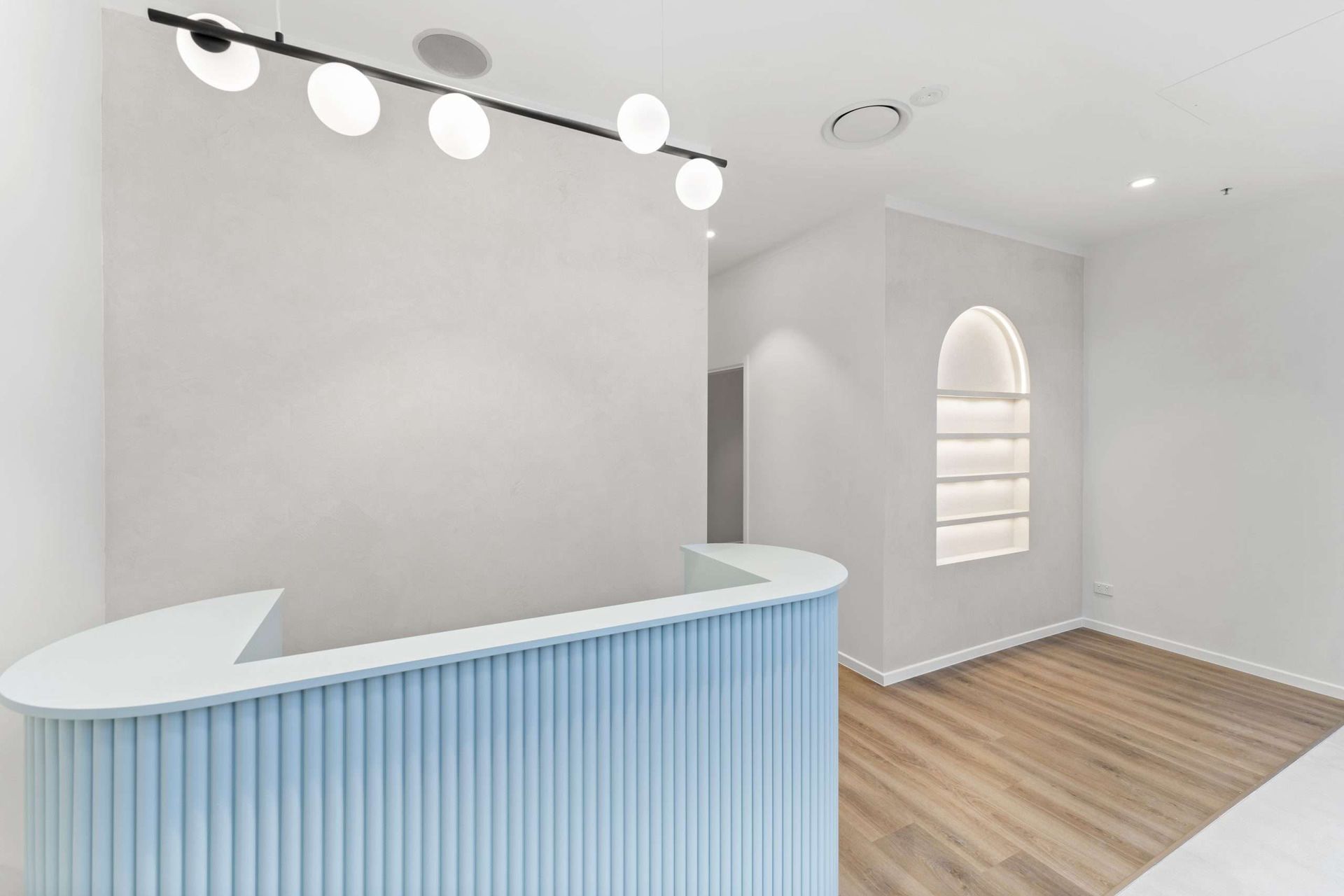 Reception area with light blue curved desk and white walls, modern minimalist design.