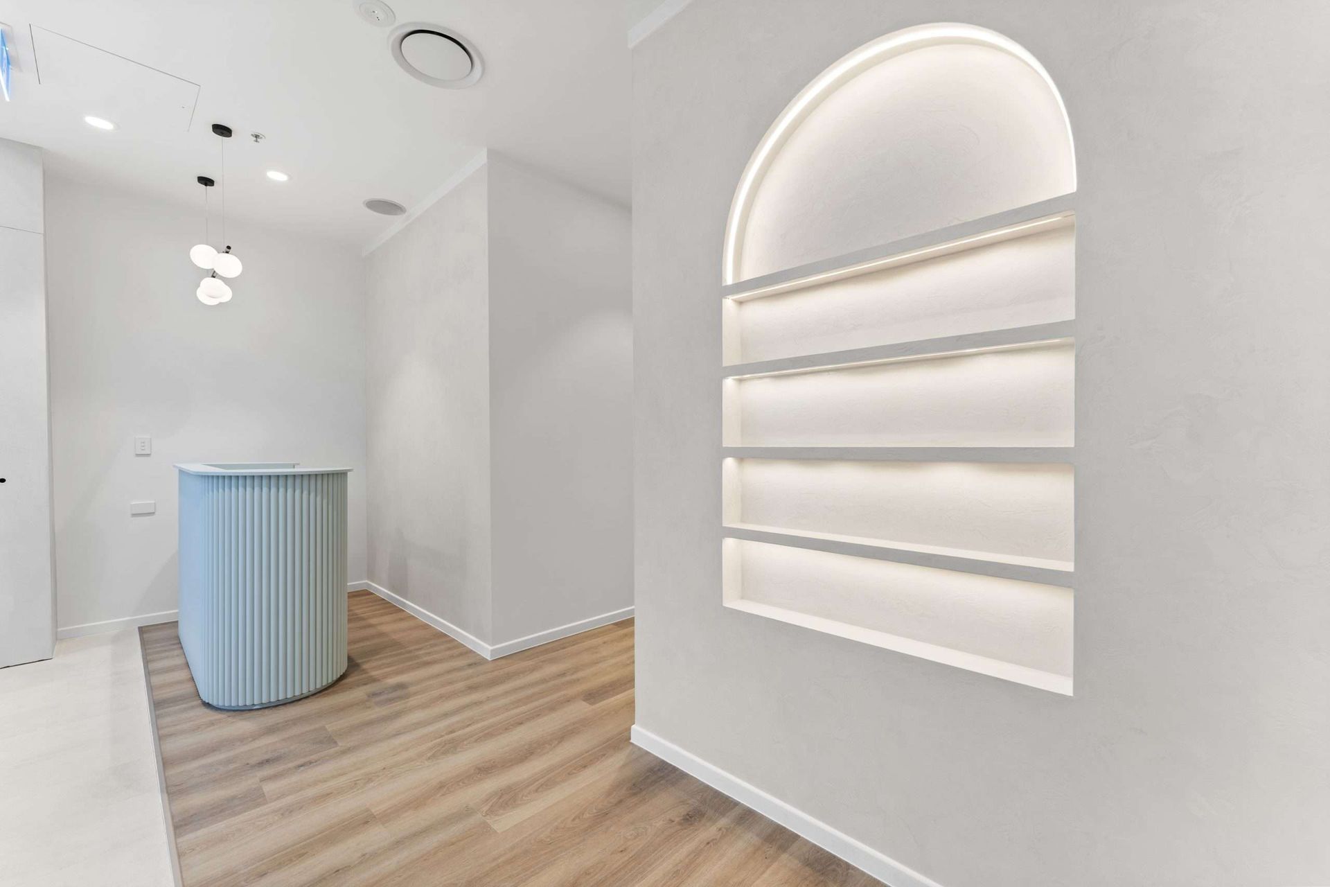 Modern white and blue reception area with arched display shelves and a blue reception desk.
