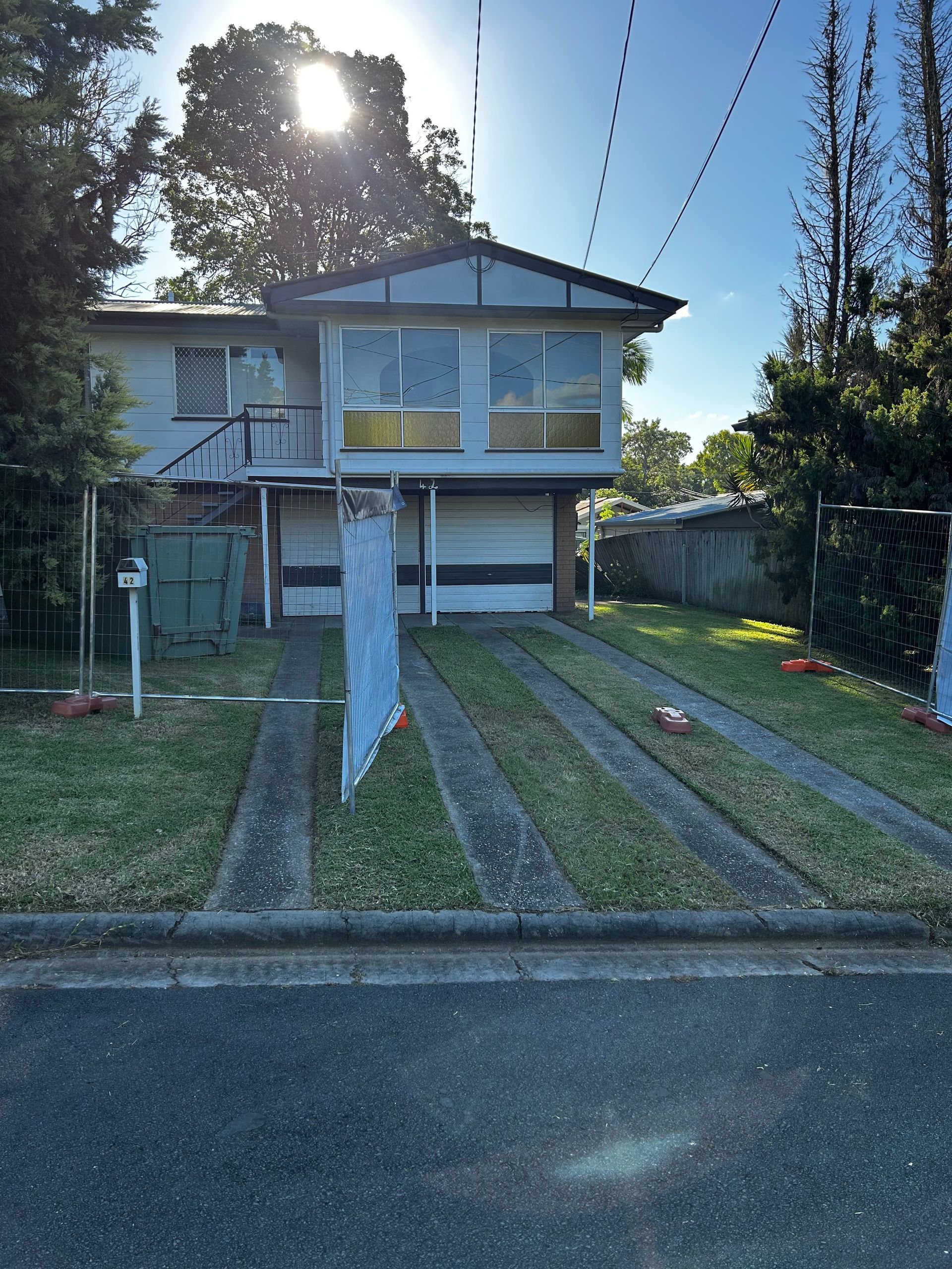 Two-story house with a driveway. The sun shines brightly above.