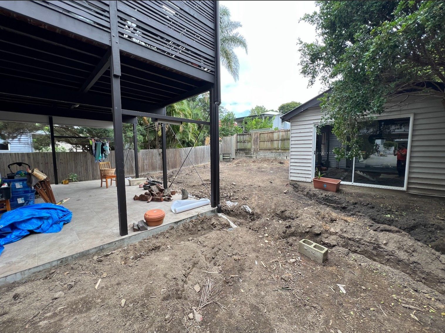 Backyard under construction, dirt pile, elevated deck, shed, and bricks.