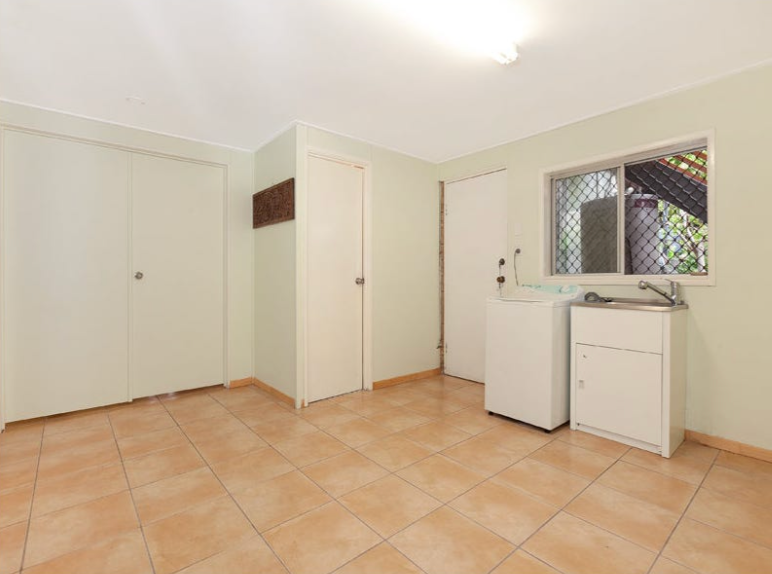 Laundry room with tiled floor, white appliances, doors, and a window.