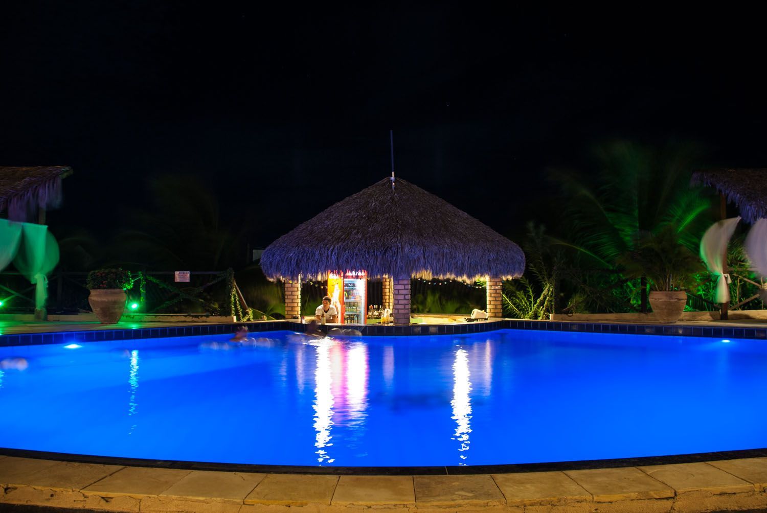 Uma grande piscina é iluminada à noite.