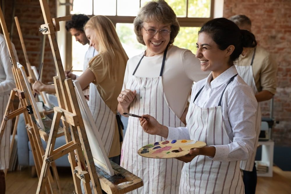 A Group Of People Are Painting On Easels In A Studio — The Red Chair Therapy in Blackwall, NSW
