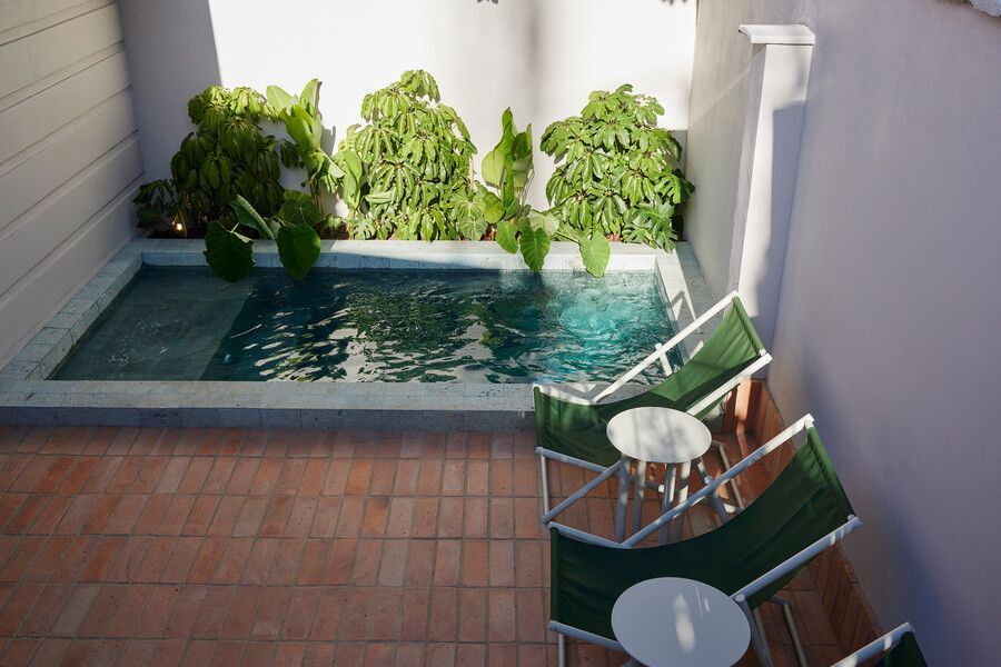 Pequeña piscina al aire libre en el Antipoda Hotel con sillas de descanso.