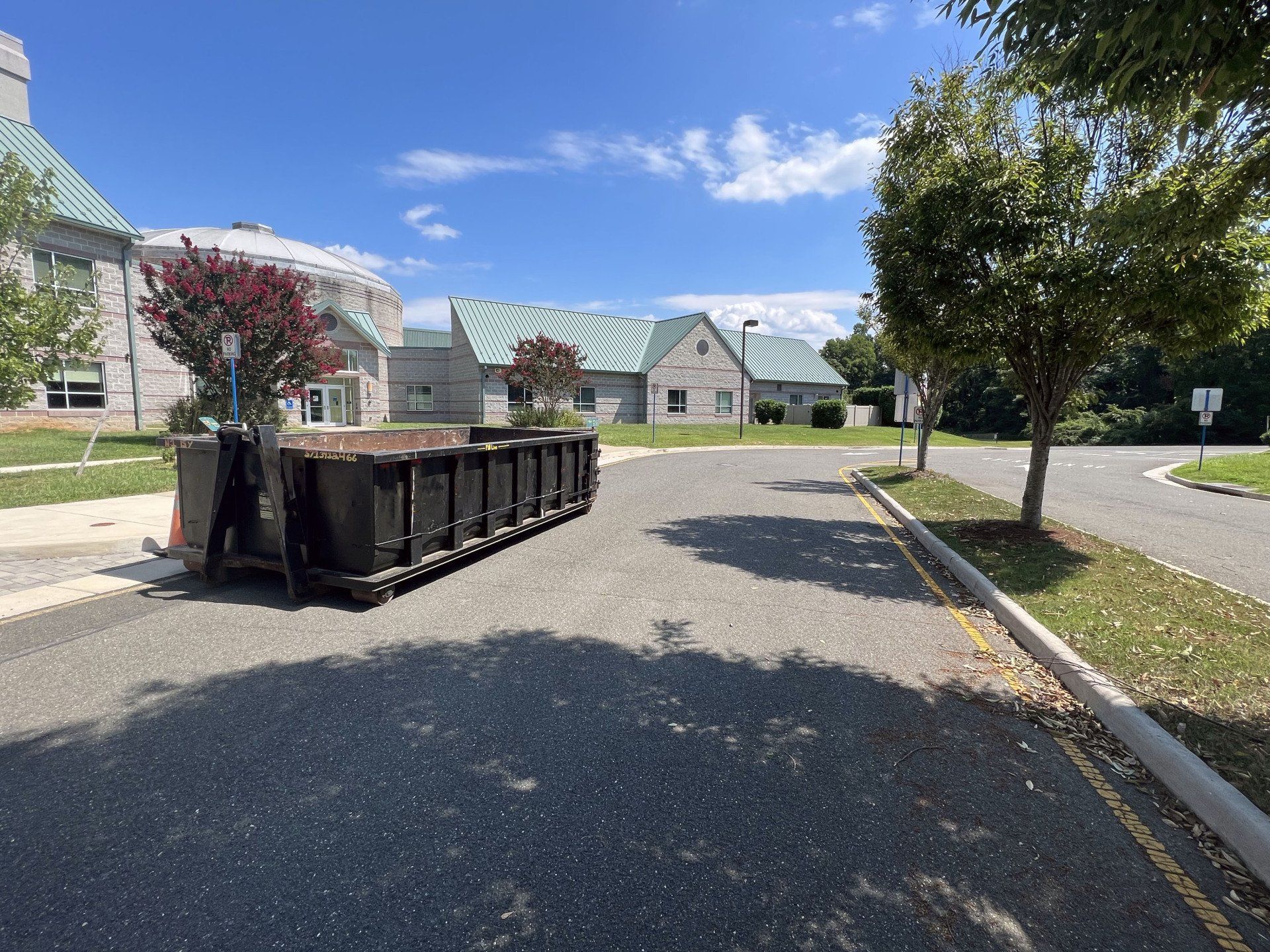 a dumpster is parked on the side of the road in front of a building .