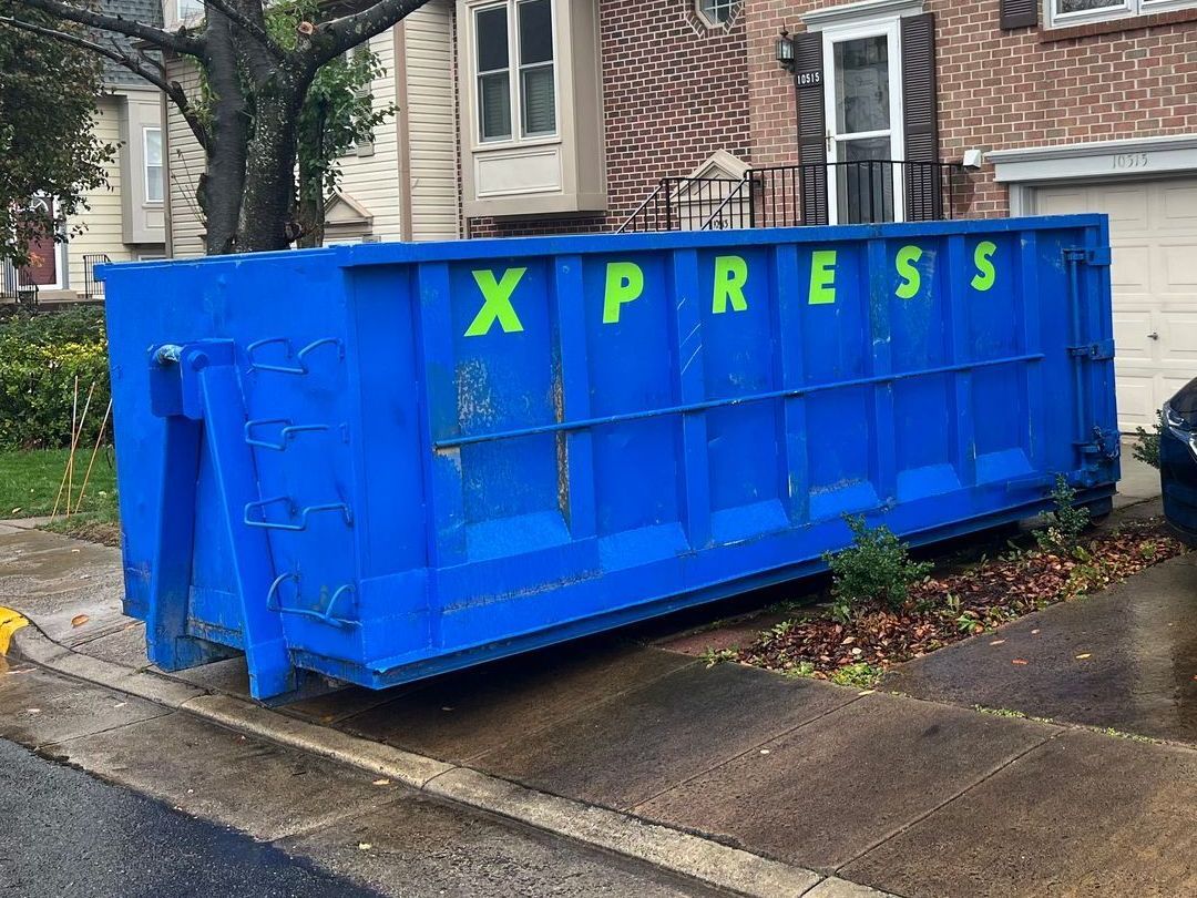 a blue dumpster is parked in front of a brick house .