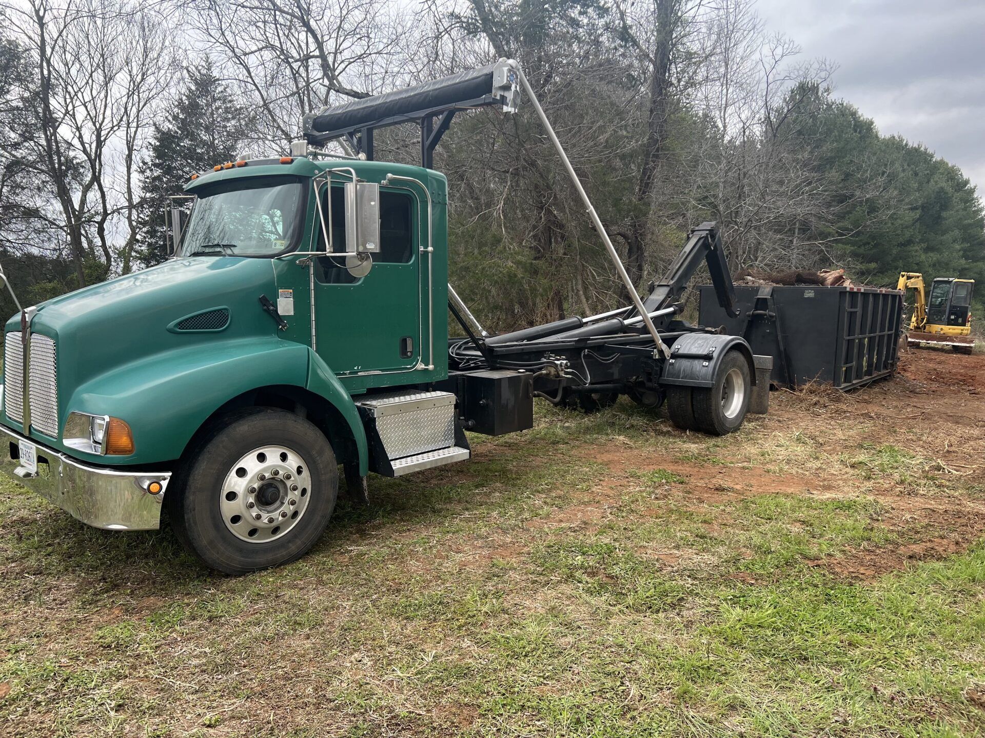 a green dump truck is parked in a grassy field .