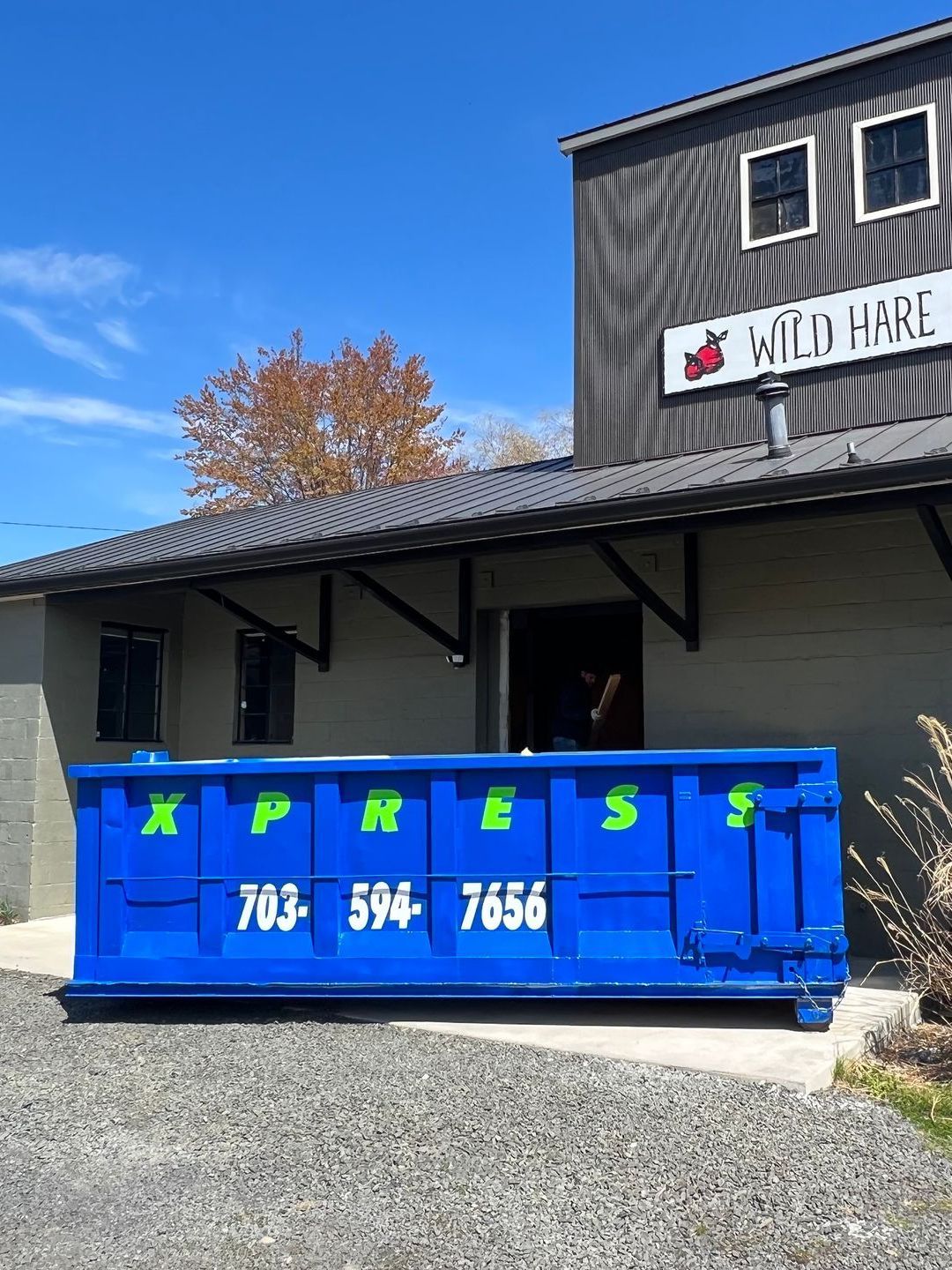a blue dumpster is parked in front of a building .
